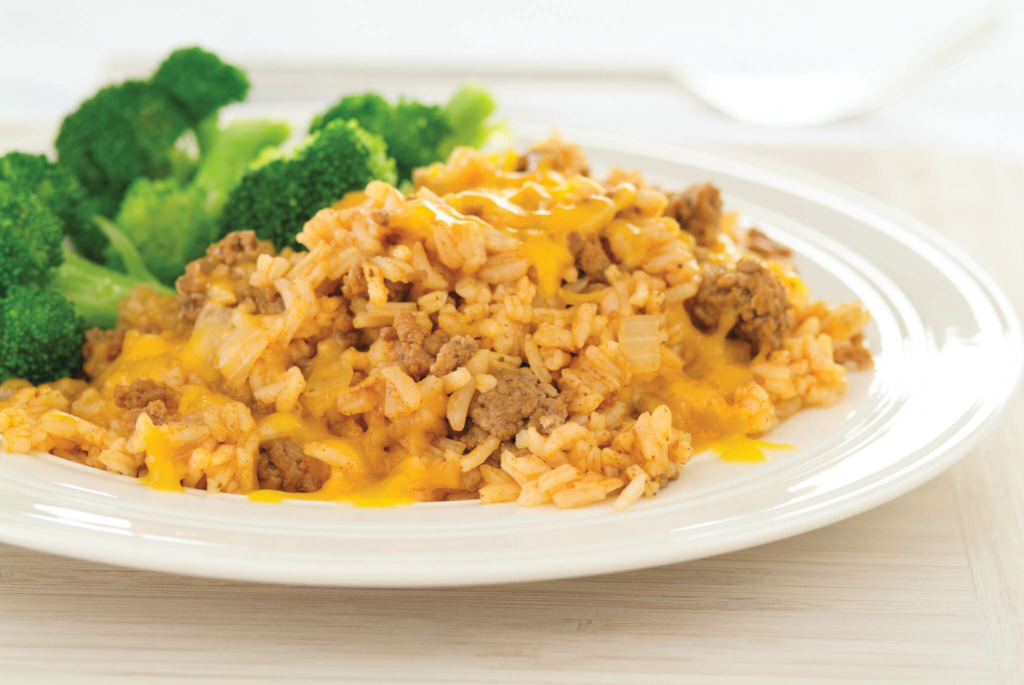 Meat and rice covered in melted cheese and a side of broccoli