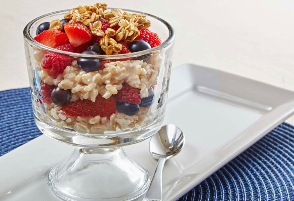 A tall glass of creamy rice layered with berries and topped with granola