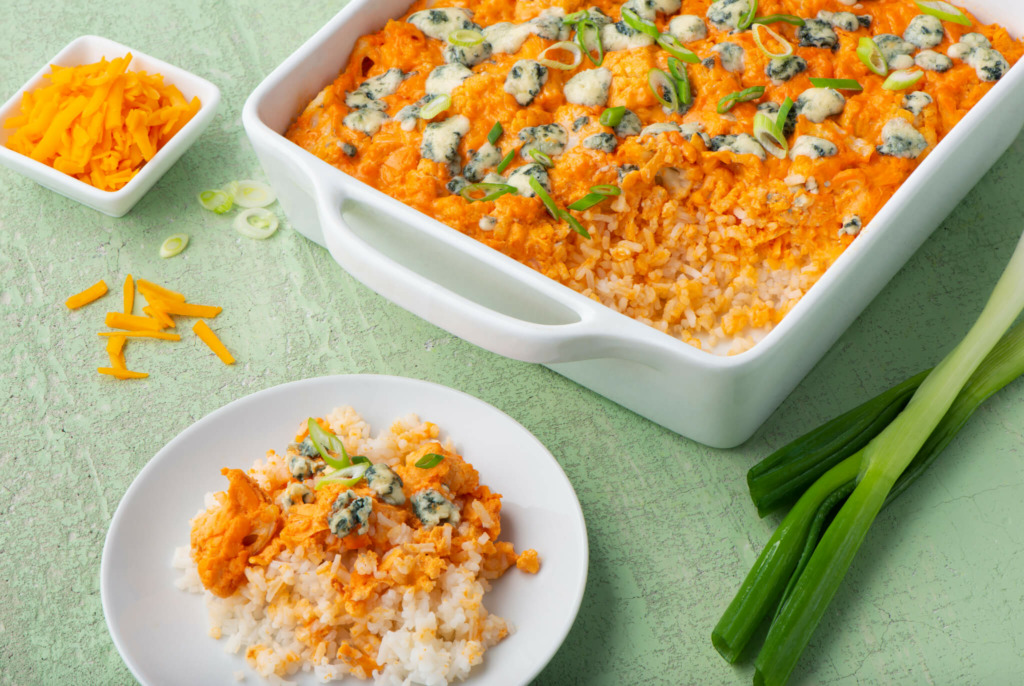 Tray of buffalo cauliflower casserole dip with rice, blue cheese and a small plate