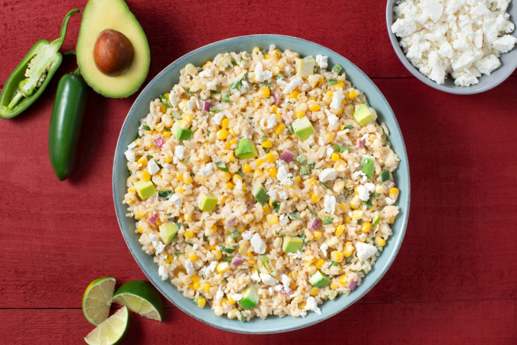 Bowl of Mexican street corn and rice with peppers and avocado