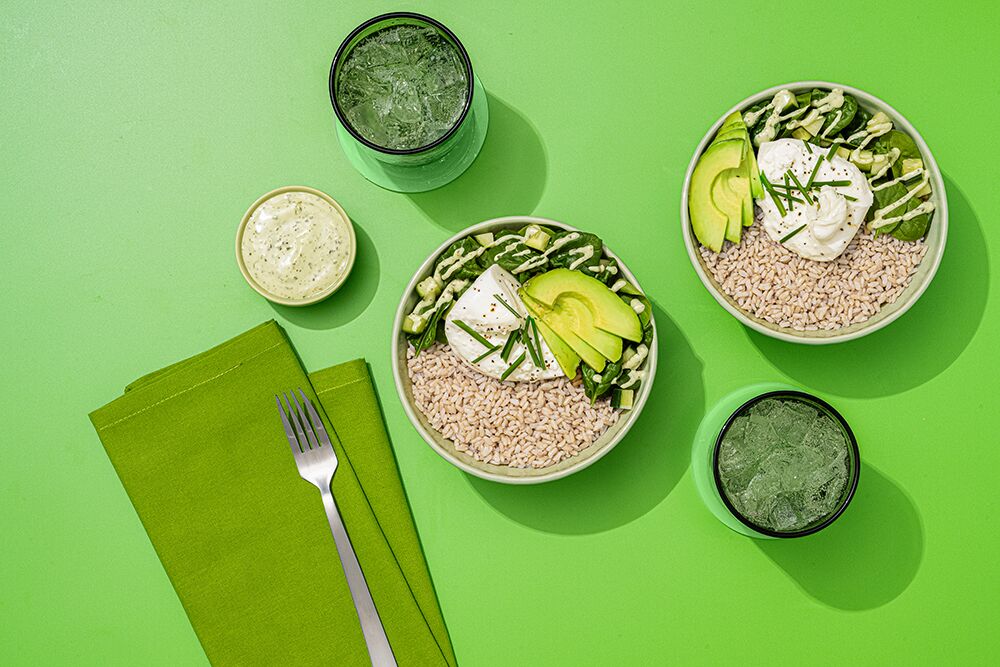 Green goddess brown rice bowl with burrata in green bowls on a green background